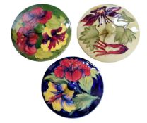 A Moorcroft Hibiscus pattern circular cover, tubelined with flowers and foliage, coloured in red and