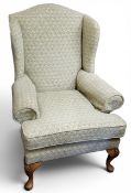 An early 20th century wing back chair, upholstered in a jacquard Adonis range peacock feather