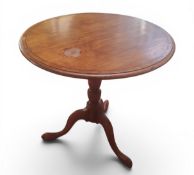 A George III style circular occasional table, tilting on baluster column, tripod legs, pad feet,