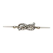AN ANTIQUE DIAMOND LOVER'S KNOT BROOCH in yellow gold and silver, designed as a lover's knot, set wi