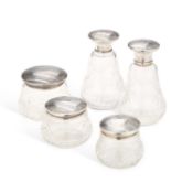 A SET OF FIVE GEORGE V SILVER-MOUNTED CUT GLASS TOILET JARS AND BOTTLES