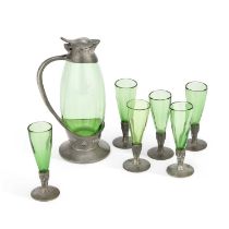 ARCHIBALD KNOX (1864-1933) FOR LIBERTY & CO A TUDRIC PEWTER AND GREEN GLASS DECANTER WITH SIX LIQUOR