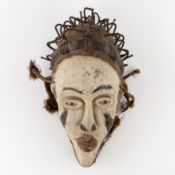 A Decorative Central African mask, sculptured wood, metal, and raffia, 20th century.