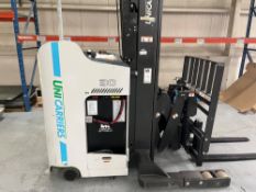 Stand-up narrow aisle reach truck forklift with side shift and carpet pole attachment.