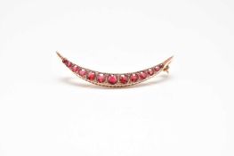 An Edwardian 9ct gold graduated red paste and diamond set crescent brooch