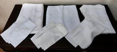 A collection of damask and lace cotton tablecloths and six large matching napkins, all with an