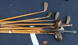 A collection of mid 20th Century golf clubs along with a single walking stick.