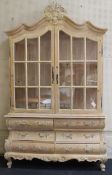 A reproduction limed tall dresser, the floral basket crested pediment over glazed doors enclosing