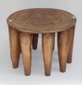 A 20th century African chip carved stool on ten conical feet, 47cm diameter