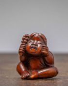 (R) NETSUKE OF A SEATED CHILD WITH RATTLE
