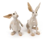 A pair of pottery sculptures of hares, modern, attributed to Sue Whimster, in appealing positions, i