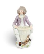 A Chelsea vase figure of a harvester, c.1758, seated with a tall basket between his legs, the top pi