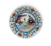 A large delftware charger, c.1760, brightly painted with a peacock between flowering plants, the rim