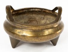 Oriental: a 19th century Chinese bronze two handled censer, standing upon three tapered feet. Apocry