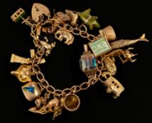 Jewellery: a 9ct yellow gold charm bracelet with heart shaped clasp, suspended with in excess of 20 