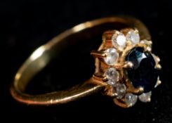 Jewellery: a yellow metal ring, marked 750 and testing as 18ct gold, set a central sapphire within a