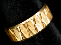 Jewellery: a yellow metal wedding band, marked 750 and testing as 18ct gold, with hatched decoration