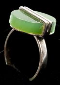 Jewellery: a white metal and nephrite jade ring, testing as silver, the oval table held in place by 