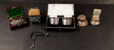 Silver: a repousse decorated pincushion of square form, Birmingham 1911, a boxed pair of napkin ring