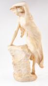 Decorative Arts: a carved alabaster figure of a woman in diaphanous dress leaning on a rocky outcrop
