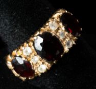 Jewellery: a 9ct gold ring set with three garnets, divded by rows of three white stones. UK size Q, 