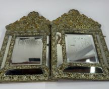 A pair of 19th century French cushion mirrors, with brass repoussé frames of repeated flower, foliat