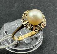 Jewellery: Yellow metal ring set with a 6.5mm cultured pearl, a floral-style surround set with six e