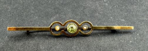 Jewellery: Yellow metal bar brooch set with a 4mm circular-cut peridot and a seed pearl either side,