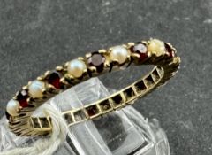 Jewellery: Yellow metal full eternity ring set with garnets, alternating with pearls (two pearls mis