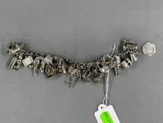 Jewellery: a silver curb link bracelet suspended with at least 30 charms, including a bulldog, a car