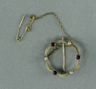 Jewellery: Yellow metal, 21.6mm, open circular brooch set with three circular-cut rubies, estimated 