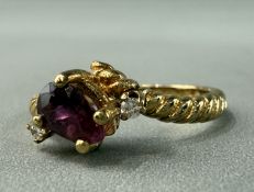 Jewellery: a yellow metal three stone ring cross over design, centre set with a pear shape ruby, est