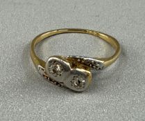 Jewellery: a yellow metal ring, marked 18ct and testing as gold, set two diamonds mounted in white m