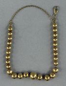 Jewellery: Yellow metal bracelet consisting of twenty-seven graduated balls, 6mm to 10mm, with a swi