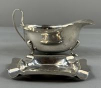 Silver: a cream jug, Birmingham 1932, standing upon three feet with castellated rim, 14cm, together 