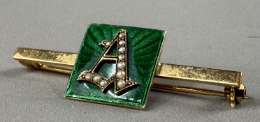 Jewellery: Yellow metal bar brooch with a 13.8mm square green enamelled centre, with the initial A, 