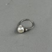Jewellery: a white metal ring set with a single 8mm cultured pearl, a single brilliant-cut diamond e