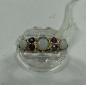 Jewellery: a 9ct yellow gold ring set three opals divided by two pairs of small rubies, UK size P, 2