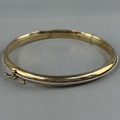 Jewellery: a 9ct gold hinged bangle, London 1987, with applied band of ropetwist white metal central