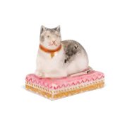 A miniature Derby figure of a cat, c.1820, recumbent on a pink cushion with its tail wrapped around,