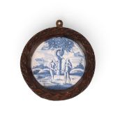 A delftware tile or plate centre, early 18th century, painted in blue with Adam and Eve beneath the 