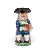 A creamware Collier Toby jug, c.1790, seated with a foaming jug of ale and an upright barrel between
