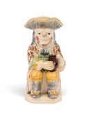 A creamware Wood type Toby jug, c.1785-90, wearing a sponged manganese coat over a green waistcoat a