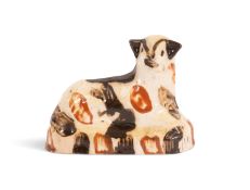 A rare Bovey Tracey creamware figure of a sheep or lamb, c.1800, recumbent with head turned to the r