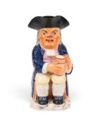 A creamware Toby jug, c.1800-20, of Ordinary type, modelled with a round-bodied jug of ale, wearing 