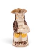 A creamware Toby jug, c.1790, seated with a foaming jug of ale and wearing a manganese coat over och