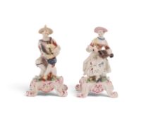 A pair of Bow figures of Harlequin and Columbine, c.1765, each seated with ankles crossed, he playin
