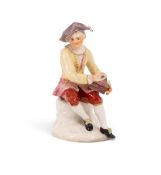 A Bow figure of a saltbox player, c.1755, seated with his saltbox in his lap, wearing a yellow jacke