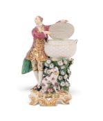 A Chelsea sweetmeat figure, c.1760, modelled as a gallant gentleman standing beside and lifting the 