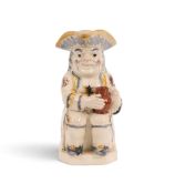 A good creamware Toby jug, c.1800, of Ordinary type, seated with an empty jug of ale, his coat spong
